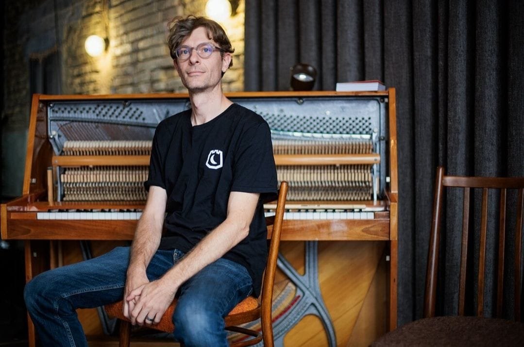 Mark Adam Harold sitting in front of the piano at the first municipality-funded grassroots music venue "Estrada" in Vilnius, Lithuania